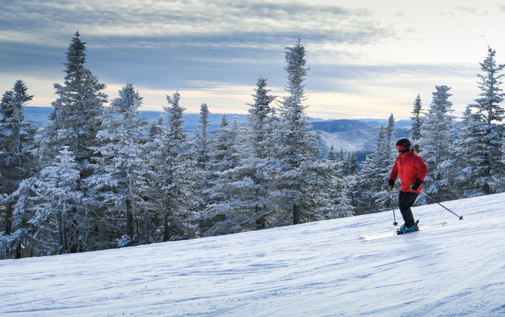 Amazing New Hampshire Ski Resorts Near Us 4 Enjoy any one of the best New Hampshire ski resorts. Man in a red jacket skies downhill.